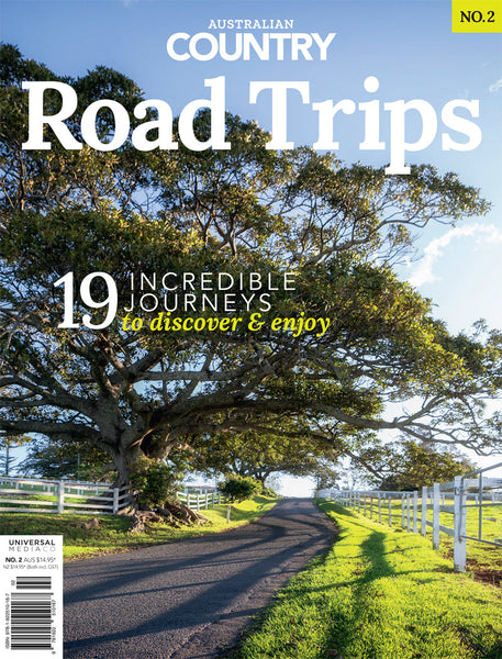 Cover of 'Australian Country Road Trips issue 2 bookazine, featuring a scenic view of a country road with trees on the side and a clear sky.